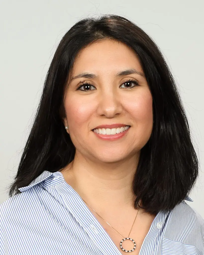 A woman with long black hair wearing a blue shirt.