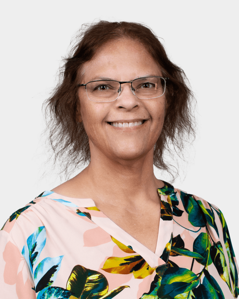 A woman with glasses and brown hair wearing a floral shirt.